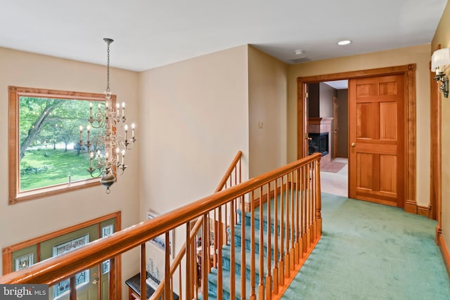 hall featuring carpet and a notable chandelier