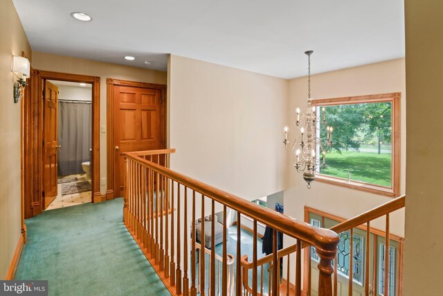 hallway featuring carpet floors and a chandelier