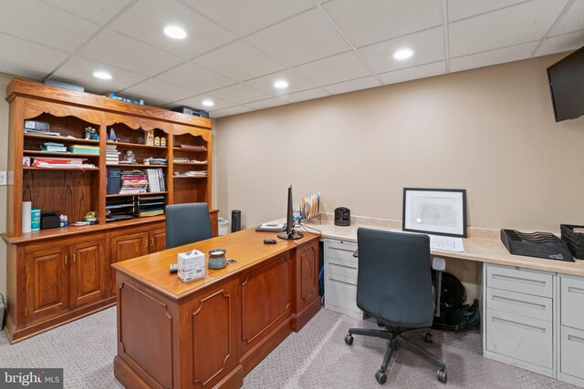 office space with built in desk, a paneled ceiling, and light colored carpet