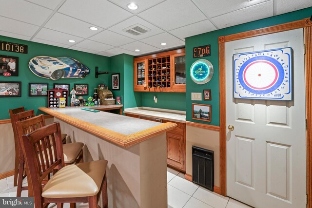 bar with light tile patterned flooring and a drop ceiling