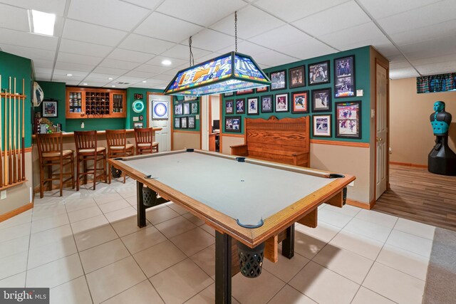 playroom with bar, light wood-type flooring, pool table, and a paneled ceiling