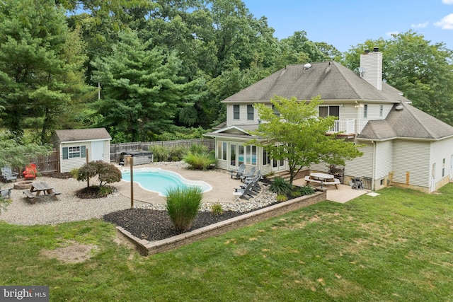 rear view of property with a lawn, a fenced in pool, a patio area, and an outbuilding