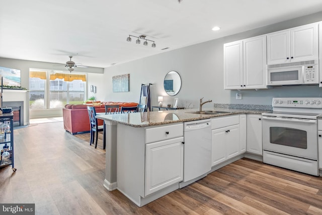 kitchen featuring sink, white cabinets, white appliances, and kitchen peninsula