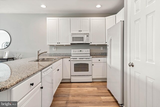 kitchen featuring sink, white appliances, white cabinetry, light stone counters, and light hardwood / wood-style floors