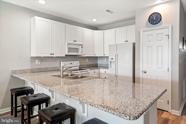 kitchen with sink, light wood-type flooring, kitchen peninsula, white appliances, and white cabinets