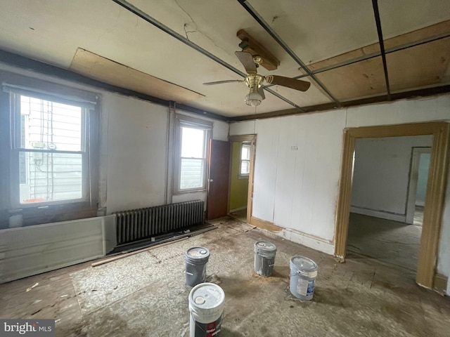 spare room featuring a healthy amount of sunlight, radiator, and ceiling fan