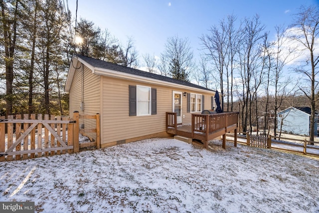 snow covered rear of property with crawl space, fence, and a deck