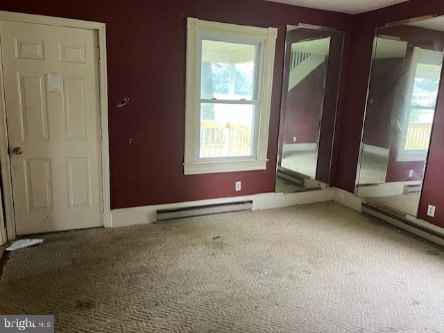 carpeted empty room with a baseboard radiator