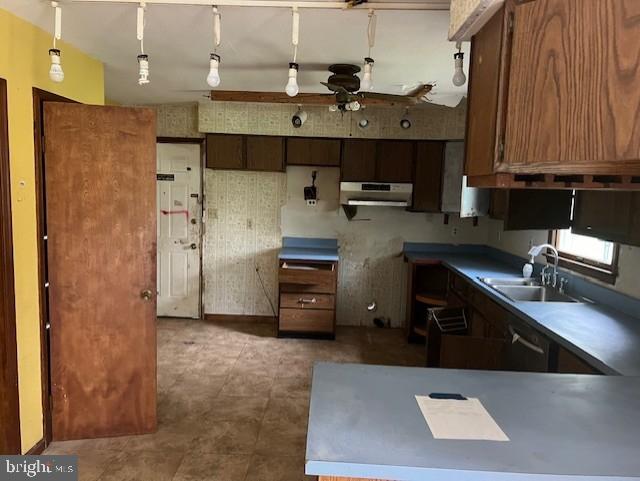 kitchen with dishwasher, hanging light fixtures, dark tile patterned flooring, extractor fan, and sink