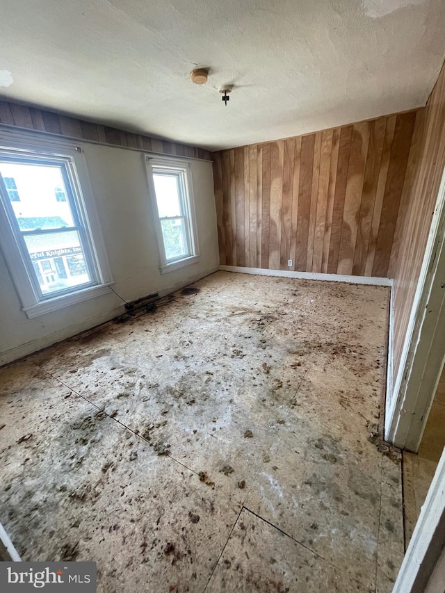 spare room featuring a textured ceiling and wooden walls