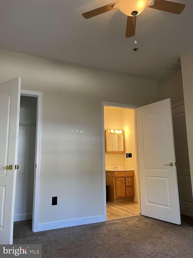 unfurnished bedroom featuring ceiling fan, ensuite bathroom, and light colored carpet