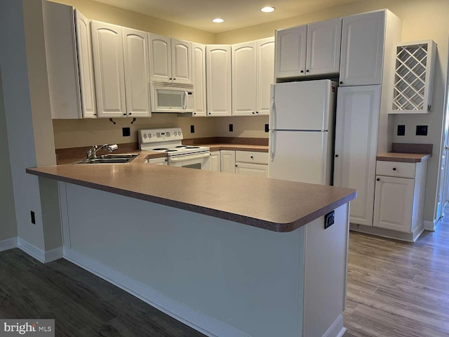 kitchen featuring white cabinetry, sink, white appliances, and kitchen peninsula