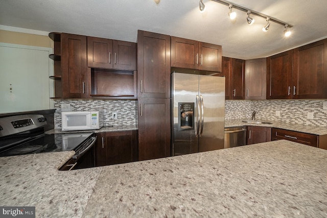 kitchen featuring sink, track lighting, backsplash, and stainless steel appliances