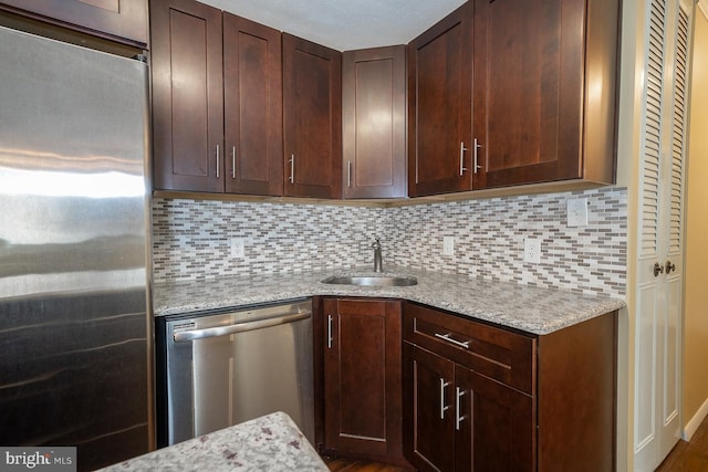 kitchen featuring backsplash, light stone countertops, sink, and appliances with stainless steel finishes