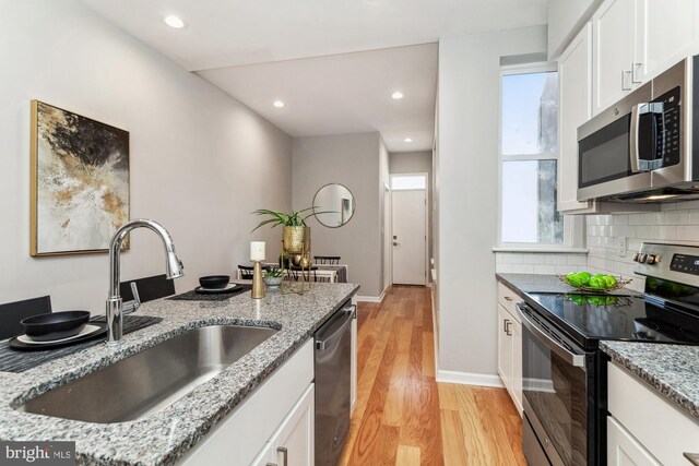 kitchen featuring appliances with stainless steel finishes, light wood-type flooring, and light stone counters