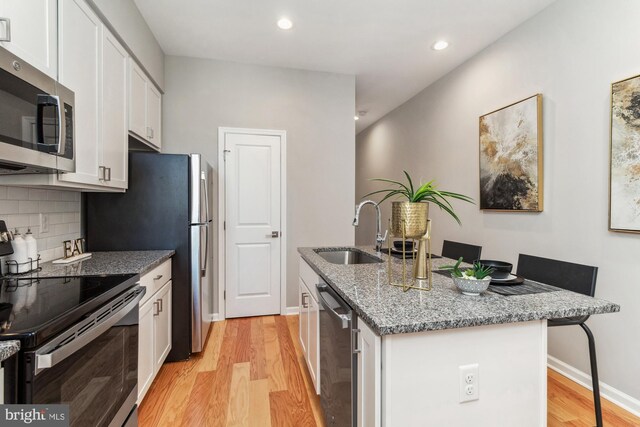 kitchen featuring light stone countertops, sink, stainless steel appliances, and light wood-type flooring