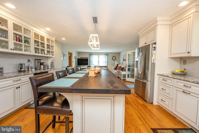 kitchen featuring wooden counters, decorative backsplash, light hardwood / wood-style flooring, and stainless steel fridge with ice dispenser