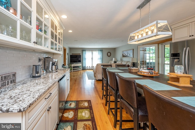 kitchen with plenty of natural light, light hardwood / wood-style flooring, stainless steel appliances, and tasteful backsplash