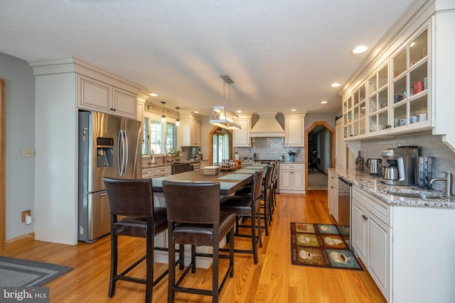 kitchen featuring light hardwood / wood-style floors, appliances with stainless steel finishes, custom exhaust hood, and sink