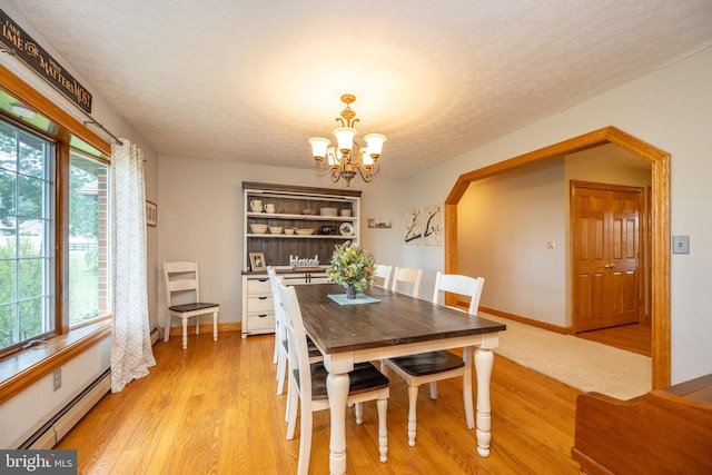 dining room featuring light hardwood / wood-style floors, a notable chandelier, baseboard heating, and a textured ceiling