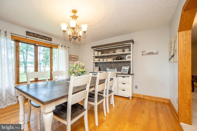 dining space featuring light hardwood / wood-style floors, a notable chandelier, and a textured ceiling