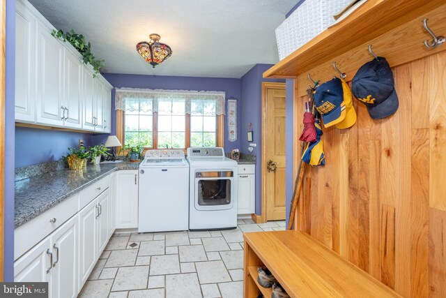 laundry area with washing machine and dryer, cabinets, and light tile patterned floors