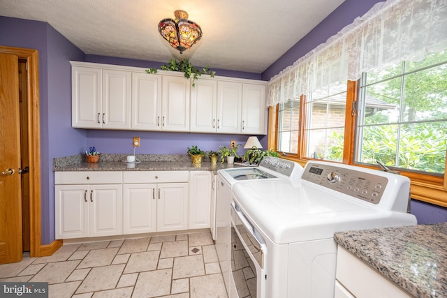 laundry room with separate washer and dryer, cabinets, and light tile patterned floors