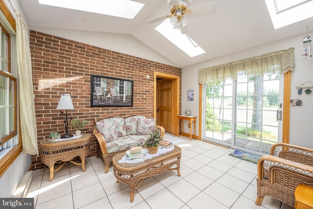 living room with light tile patterned flooring, brick wall, vaulted ceiling with skylight, and ceiling fan