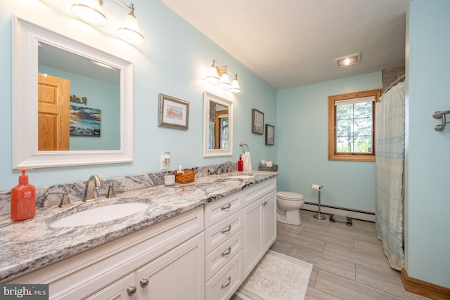 bathroom featuring a baseboard heating unit, tile patterned floors, dual vanity, and toilet