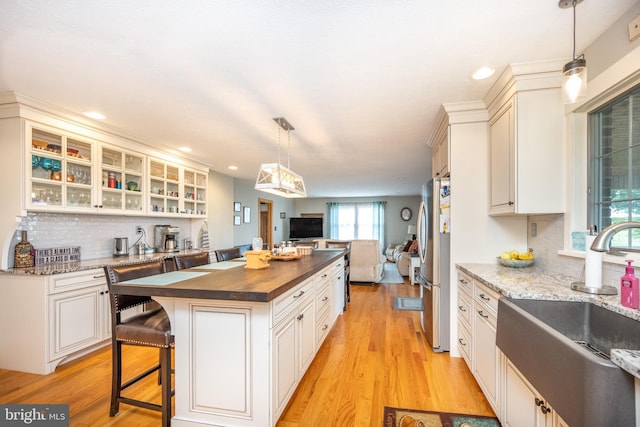 kitchen with stainless steel refrigerator, wood counters, light hardwood / wood-style floors, and tasteful backsplash