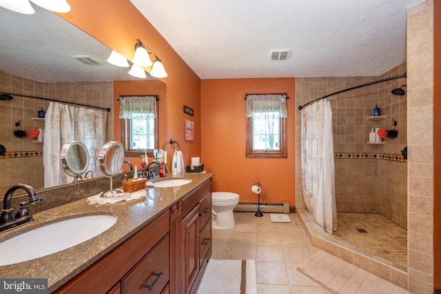 bathroom with a baseboard radiator, toilet, a wealth of natural light, and dual bowl vanity