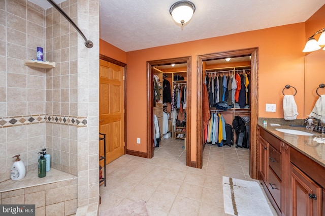 bathroom featuring vanity, tile patterned floors, and a tile shower