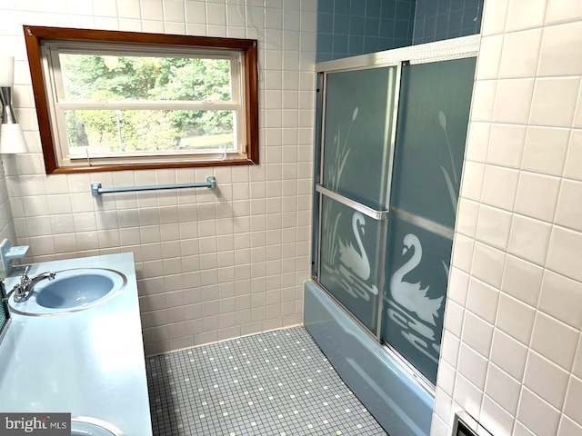 bathroom featuring bath / shower combo with glass door, vanity, tile patterned floors, and tile walls