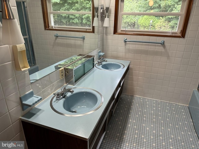 bathroom with tile patterned floors, tile walls, and a healthy amount of sunlight