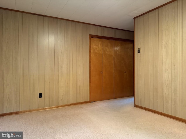 empty room with crown molding, light colored carpet, and wooden walls