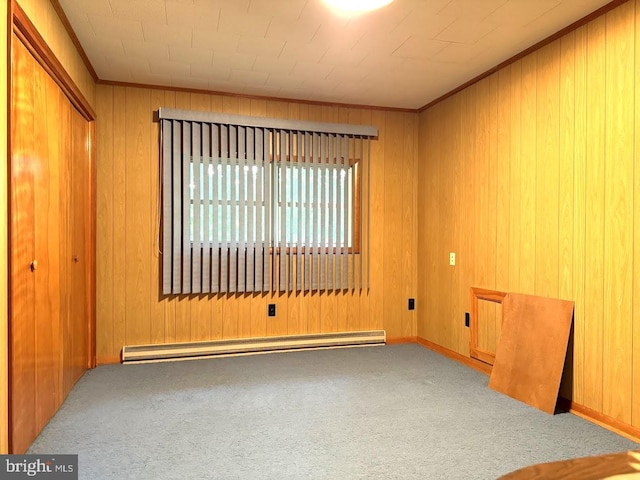 carpeted empty room featuring wood walls and a baseboard radiator