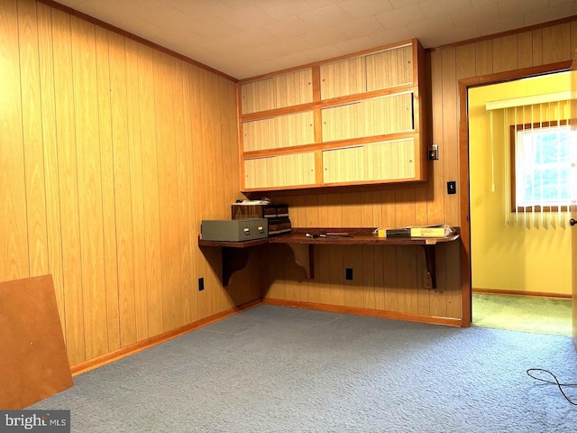 office with light carpet, wood walls, and built in desk