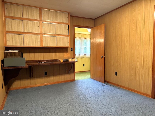 interior space with ornamental molding, light colored carpet, and wooden walls