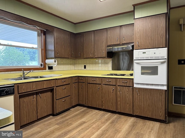 kitchen featuring light wood-type flooring, white appliances, ornamental molding, sink, and backsplash