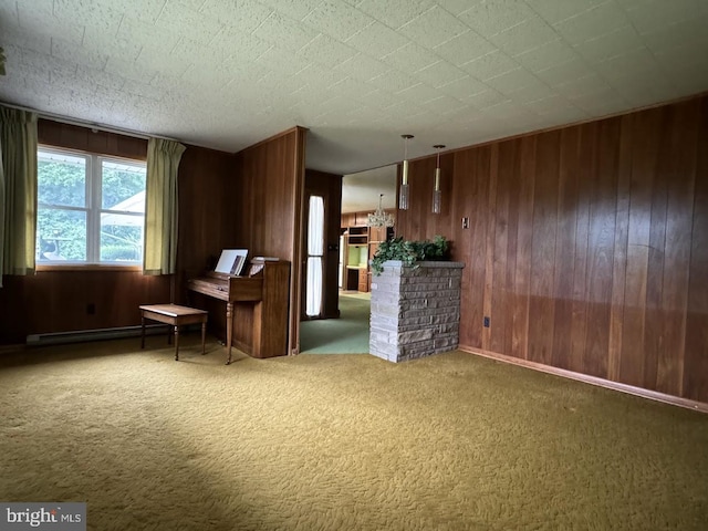 unfurnished room featuring wood walls, carpet, a textured ceiling, and a baseboard heating unit