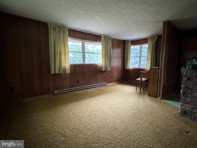 carpeted empty room featuring wood walls and a baseboard radiator