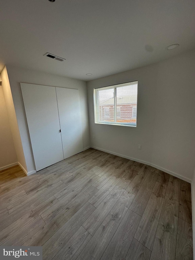 unfurnished bedroom with a closet and light hardwood / wood-style flooring