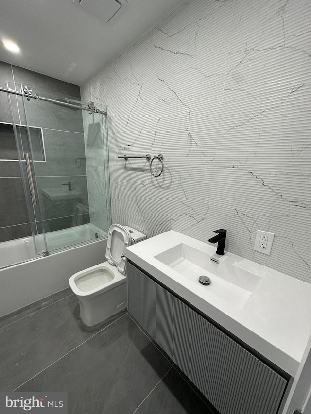 full bathroom featuring vanity, tile patterned floors, combined bath / shower with glass door, and toilet