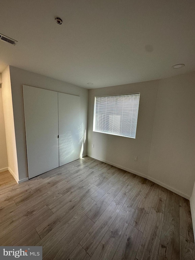 unfurnished bedroom with light hardwood / wood-style flooring and a closet