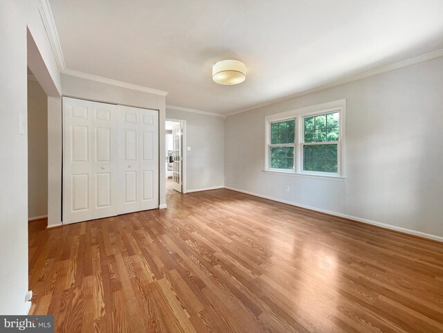 unfurnished bedroom featuring crown molding, wood-type flooring, and a closet