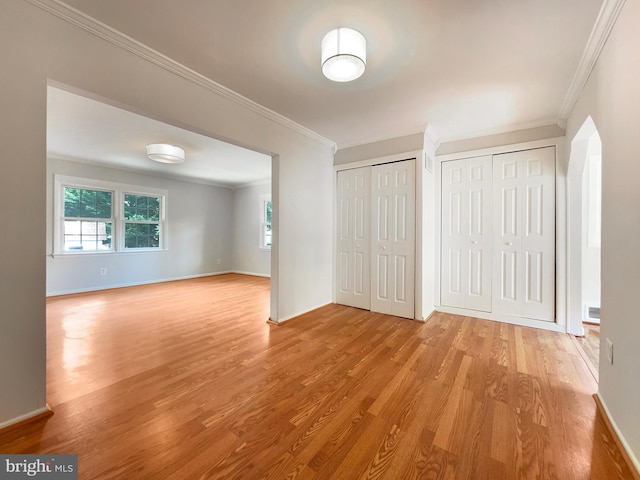 interior space featuring multiple closets, ornamental molding, and light hardwood / wood-style flooring