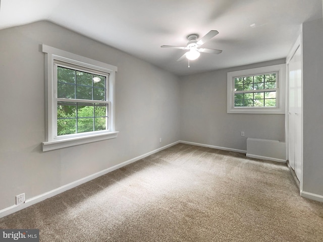 empty room with ceiling fan, vaulted ceiling, and carpet