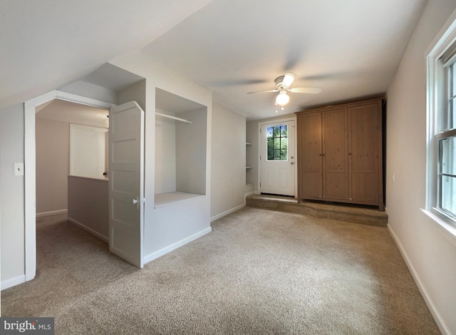 carpeted entrance foyer with vaulted ceiling and ceiling fan