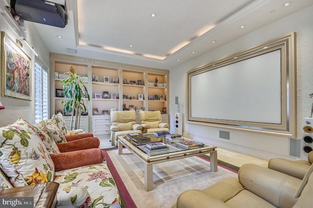 home theater room with a raised ceiling and built in features