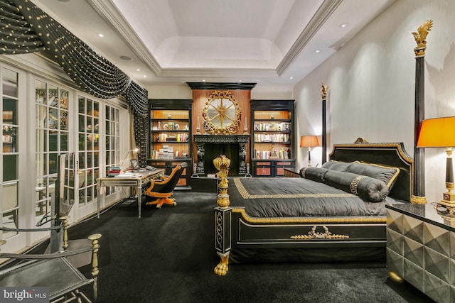 carpeted bedroom featuring a large fireplace and a tray ceiling